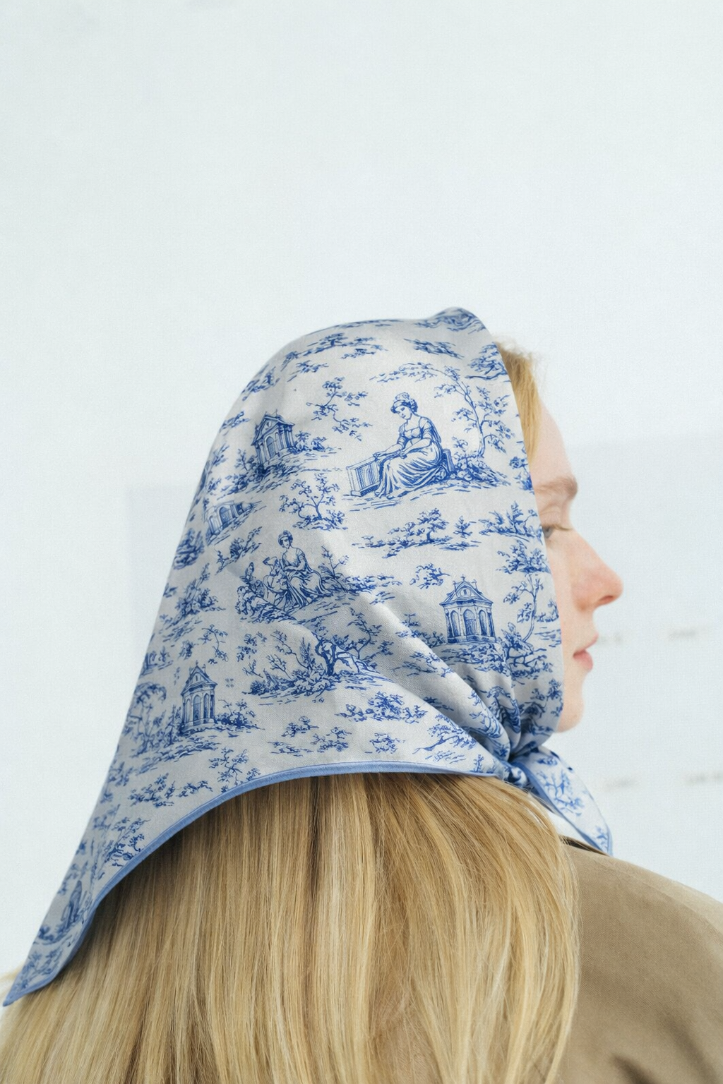 Foulard en soie bleu à motif toile de Jouy porté sur la tête, allure élégante et féminine intemporelle