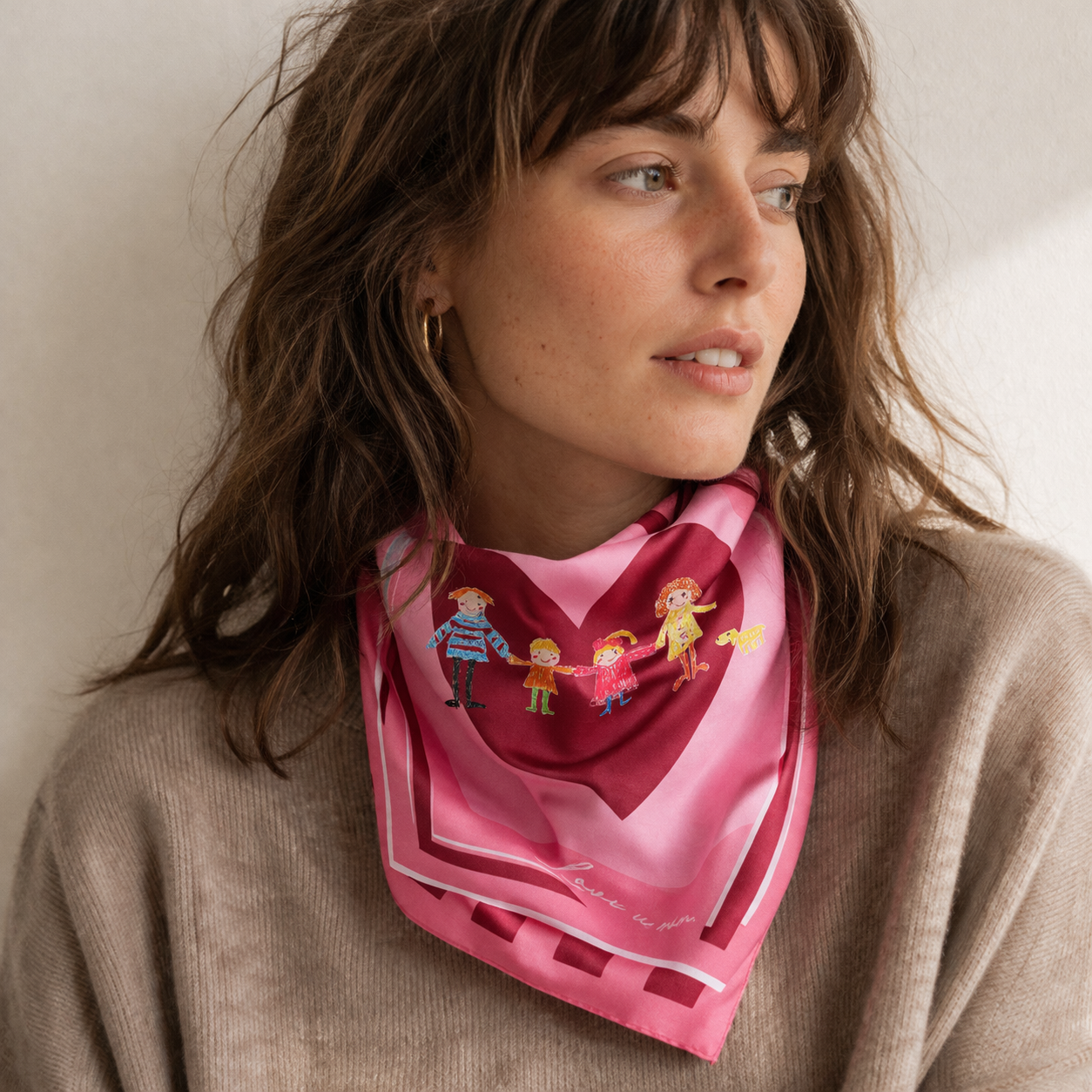 Femme portant un foulard en soie rose avec motif cœur et illustration de famille