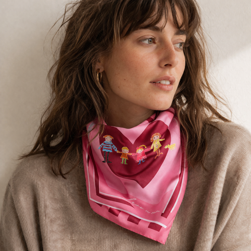 Femme portant un foulard en soie rose avec motif cœur et illustration de famille